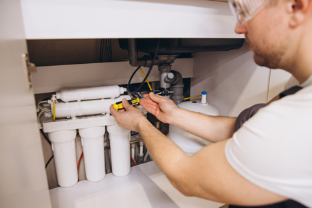 Plumber Installing Water Filter System Under Kitchen Sink